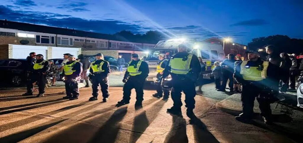 Police officers in riot gear respond to anti-immigration disorder in Thetford as crowds gather on a residential street during a third night of protests.